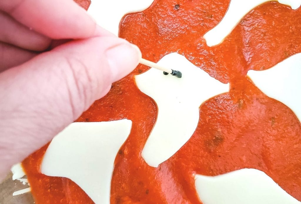 Drawing ghost eyes on pepperoni dip