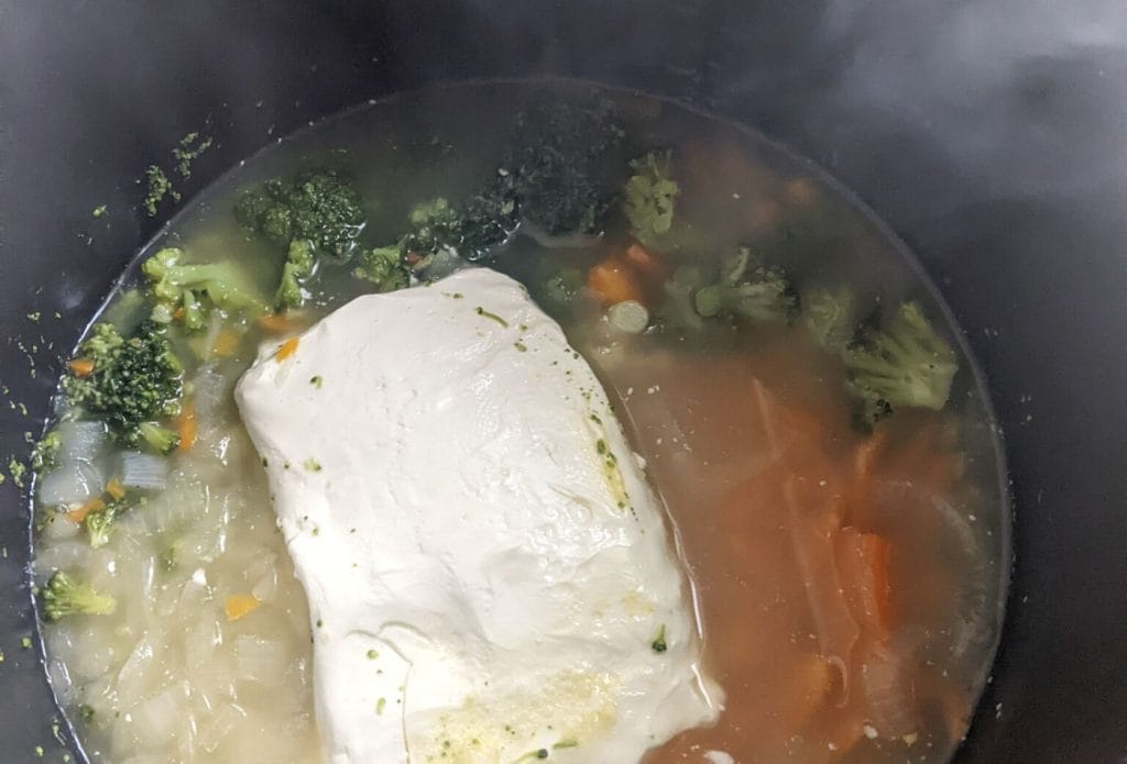 instant pot with broccoli soup veggies and a block of cream cheese