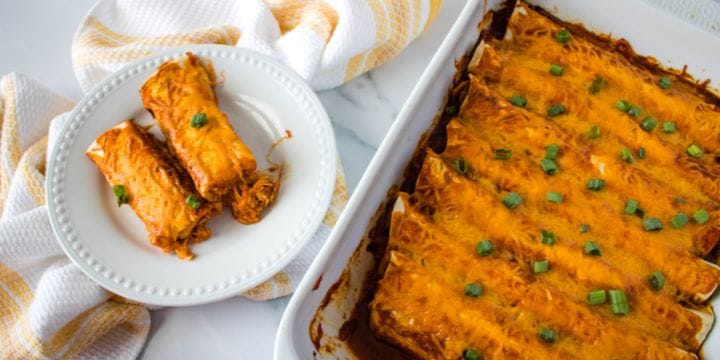 leftover pulled pork enchiladas in a dish with two on a plate on a board