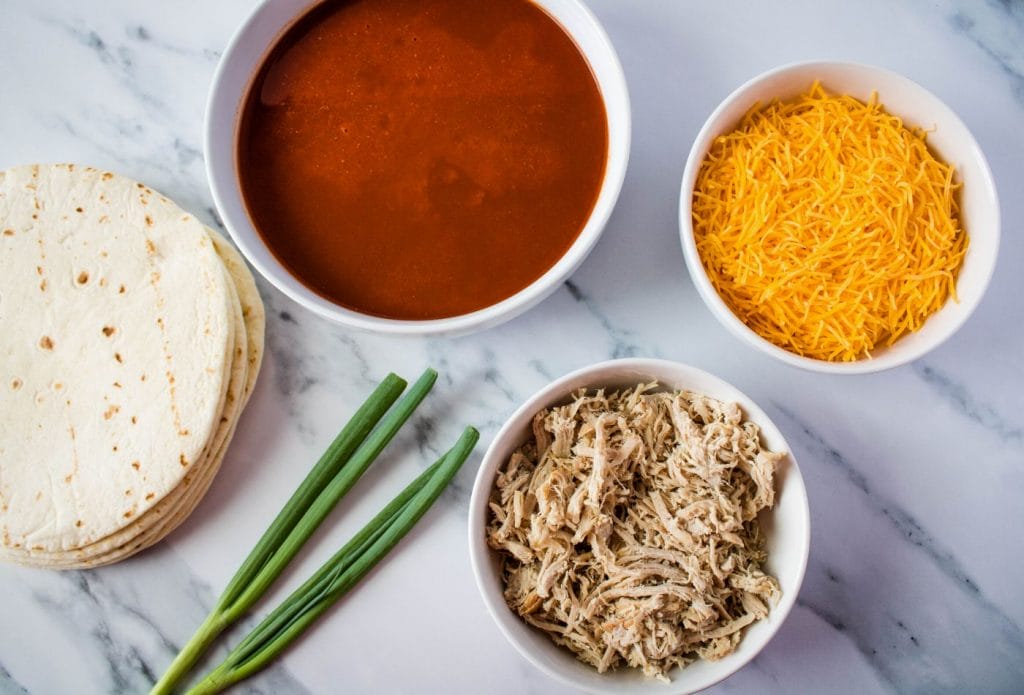 ingredients for pork enchiladas in bowls on a counter