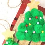 Christmas tree ornament made from pom poms and wooden stars on a sled