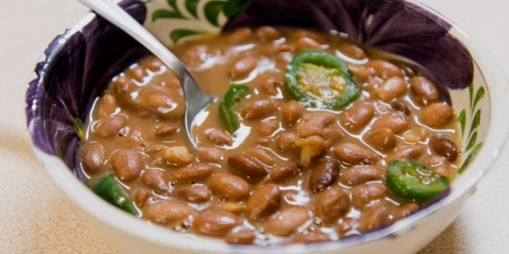 bowl of pinto beans topped with jalapeno slices