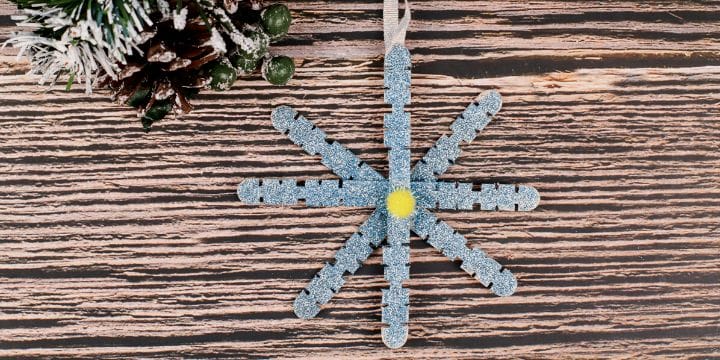 glitter snowflake ornament on a board by some garland