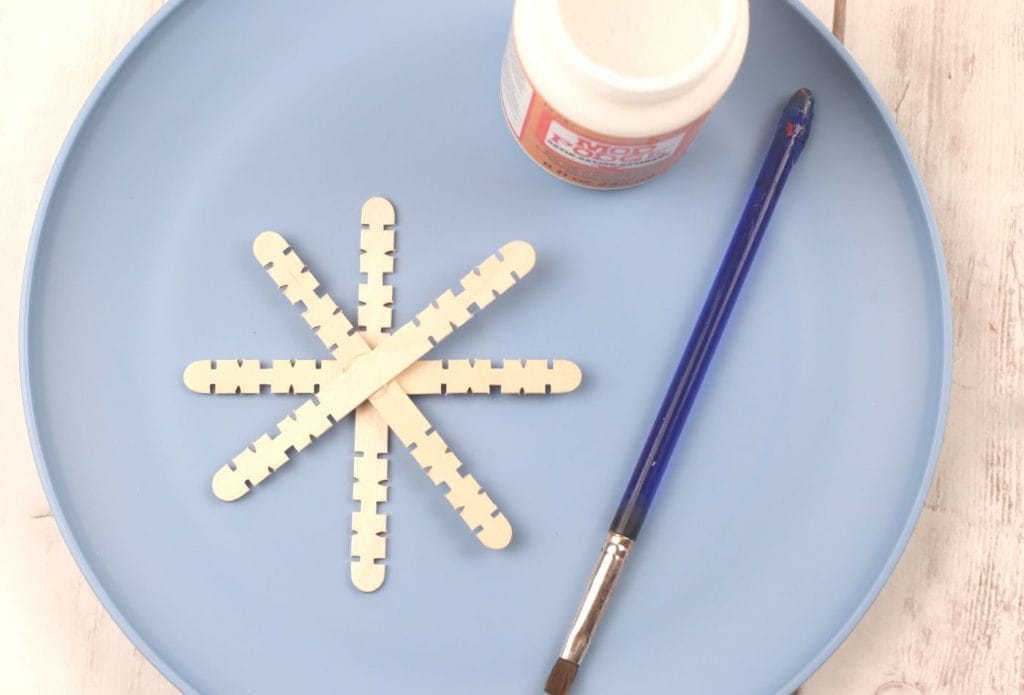 popsicle sticks glued into a snowflake with a paintbrush and some mod podge to paint on