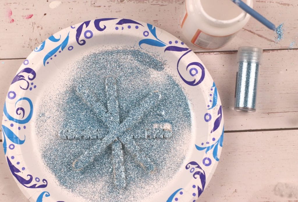 glitter sprinkled on a popsicle stick snowflake