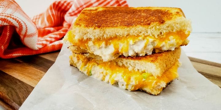 tuna melt sandwich halves stacked on a cutting board