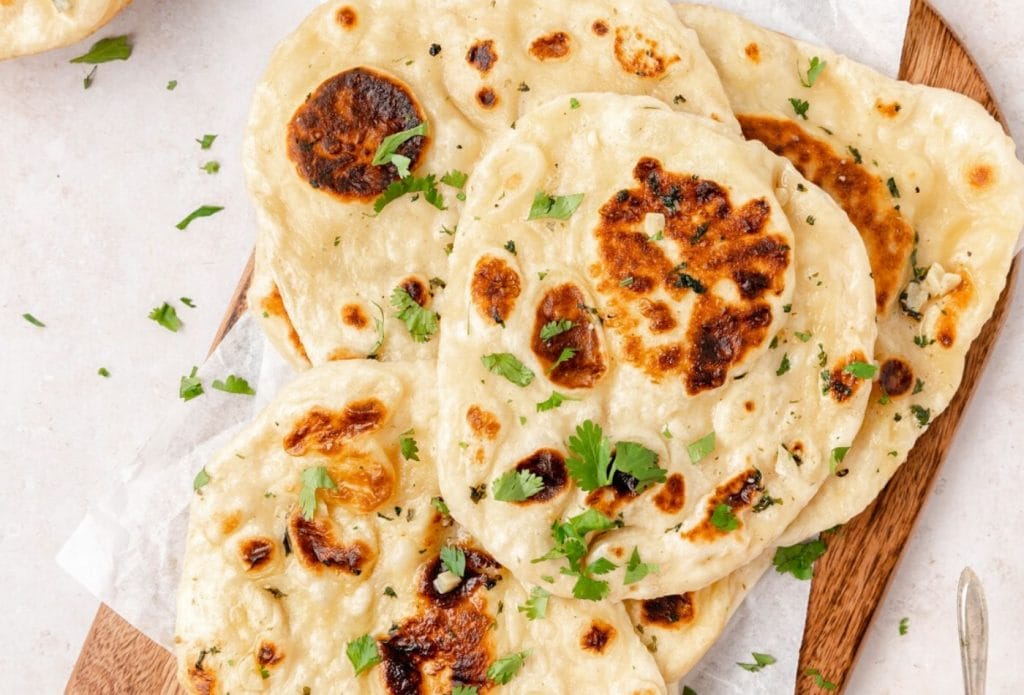 sourdough naan on a tray garnished with herbs