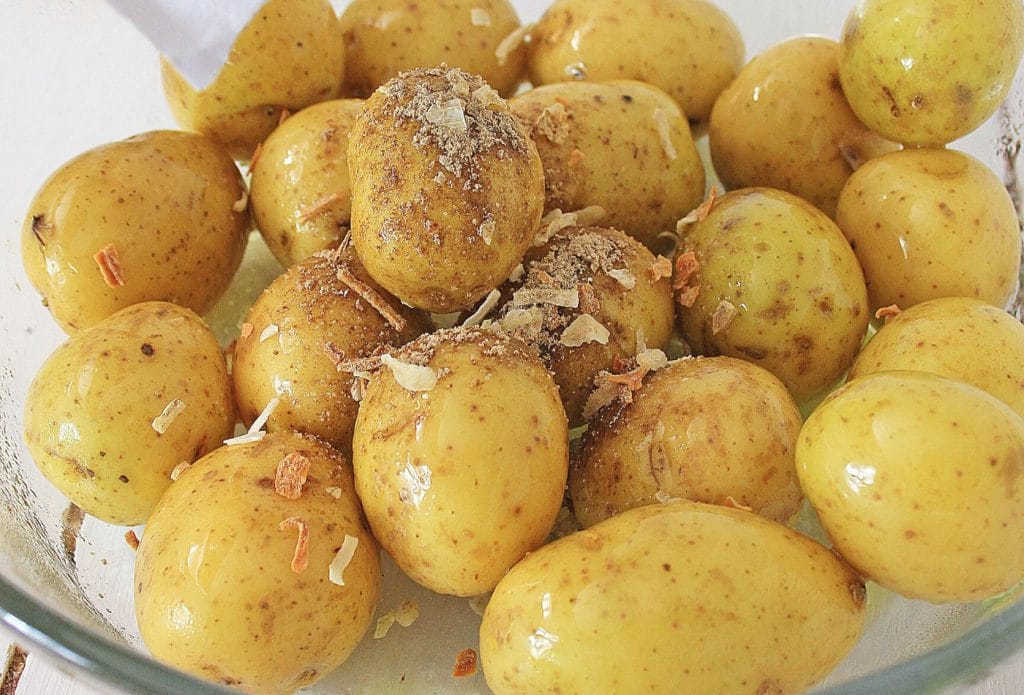 baby potatoes on a plate with spices being sprinkled on
