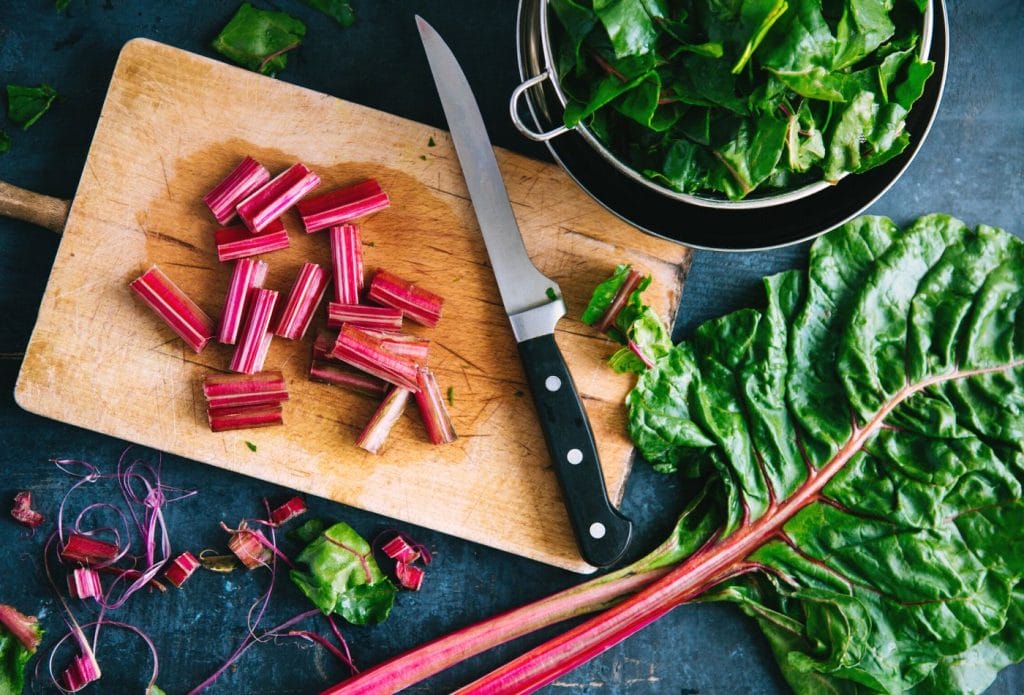 chopping and destemming swiss chard on a cutting board
