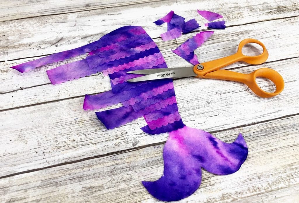 strips of painted coffee filter being layered on a mermaid tail