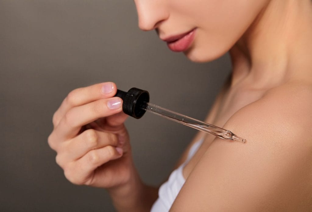 applying healthy body oil to skin with a dropper