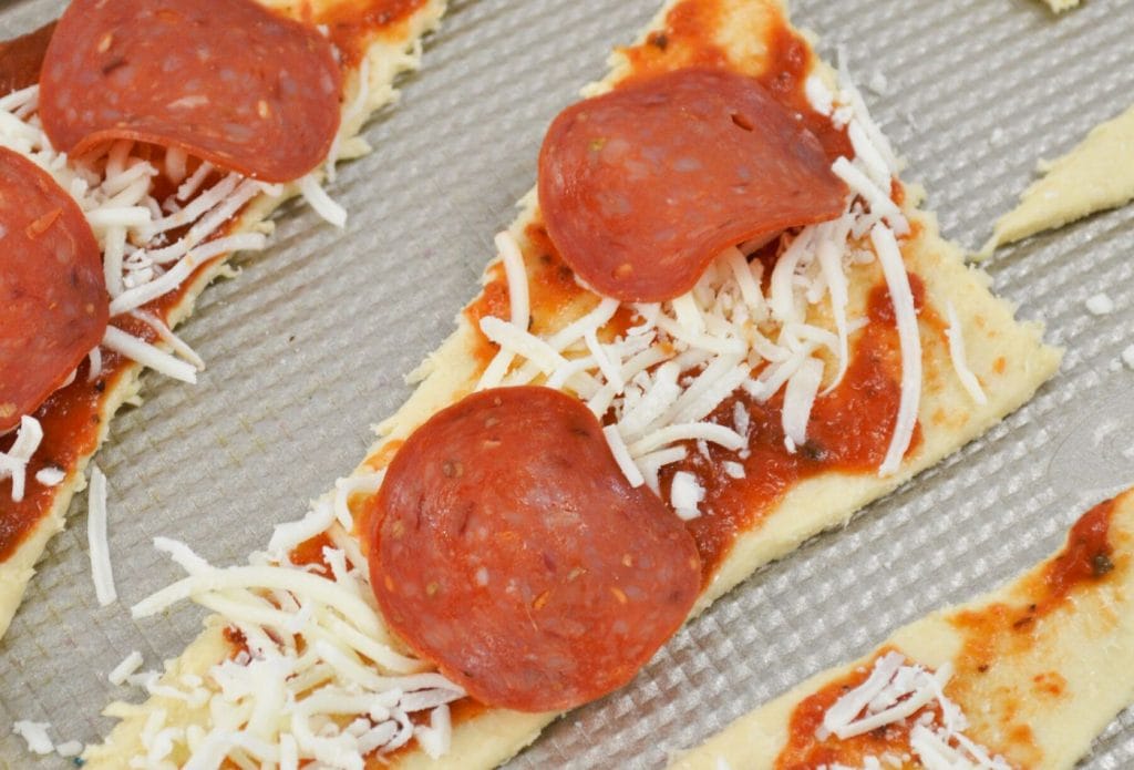 pepperoni, marinara sauce, and cheese on a crescent triangle about to be a pepperoni meatball roll up