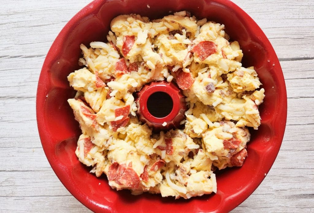 pepperoni monkey bread being mixed in a bundt pan