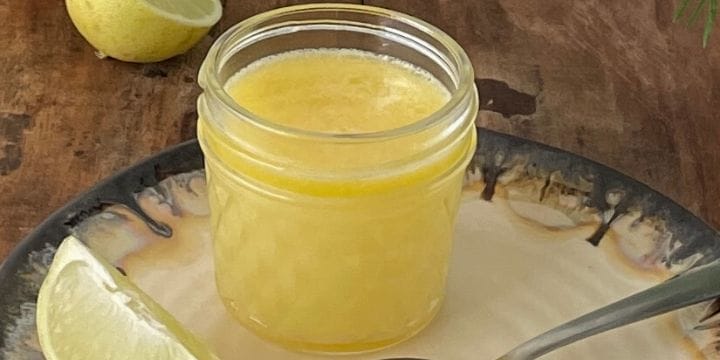 small batch lemon curd in a small jar on a brown and white plate