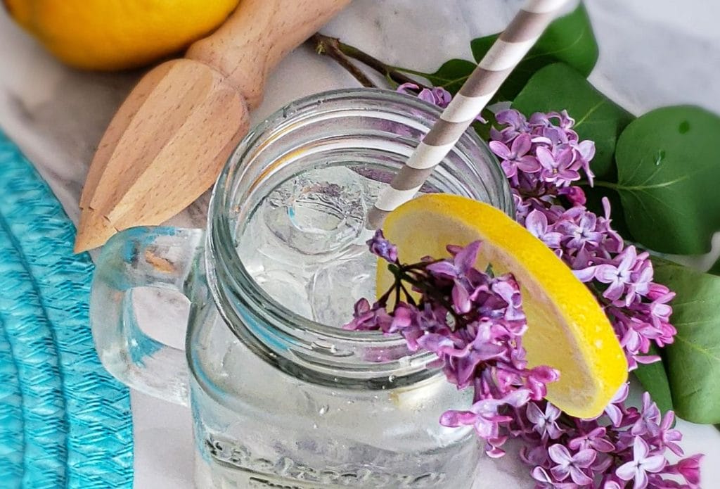 top view of a glass of lemonade with lilacs in it