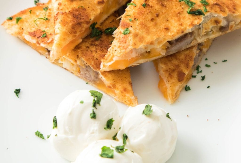 steak quesadillas with sour cream on a plate