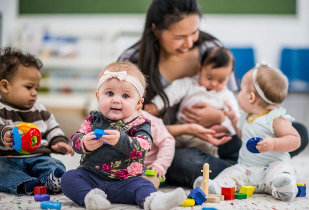 family daycare provider playing with kids on the floor