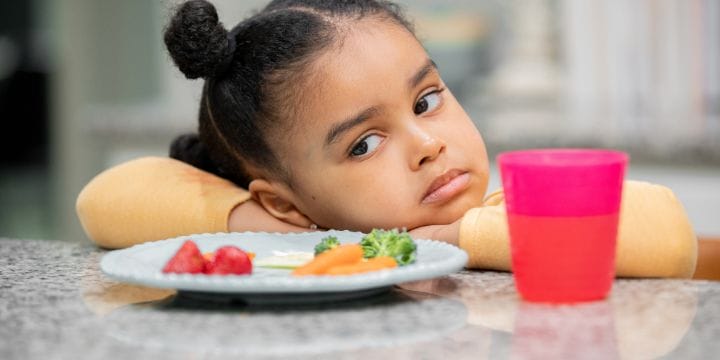 sad child at the table not wanting to eat