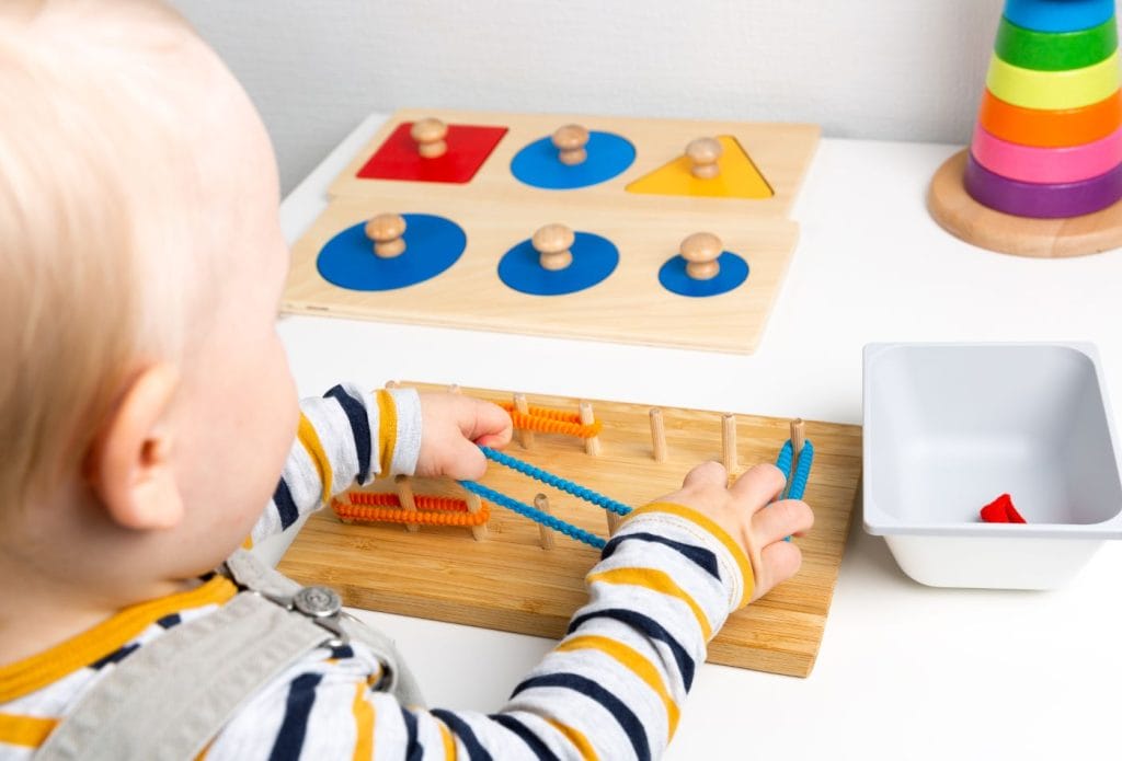 a toddler stretching fuzzy bands onto pegs