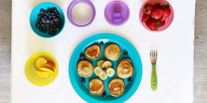 pancakes and fruit toppings with a glass of milk