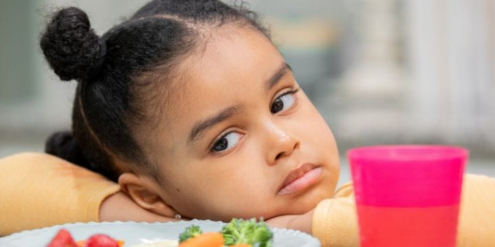 a picky eater making the bad face at her plate of food