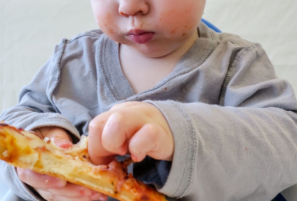 a toddler eating a piece of pizza