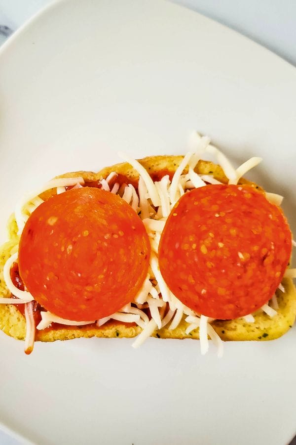 garlic toast with pizza sauce, cheese and pepperonis on top