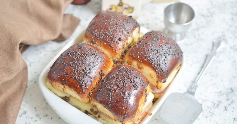 poppyseed topped ham and cheese sliders in a dish