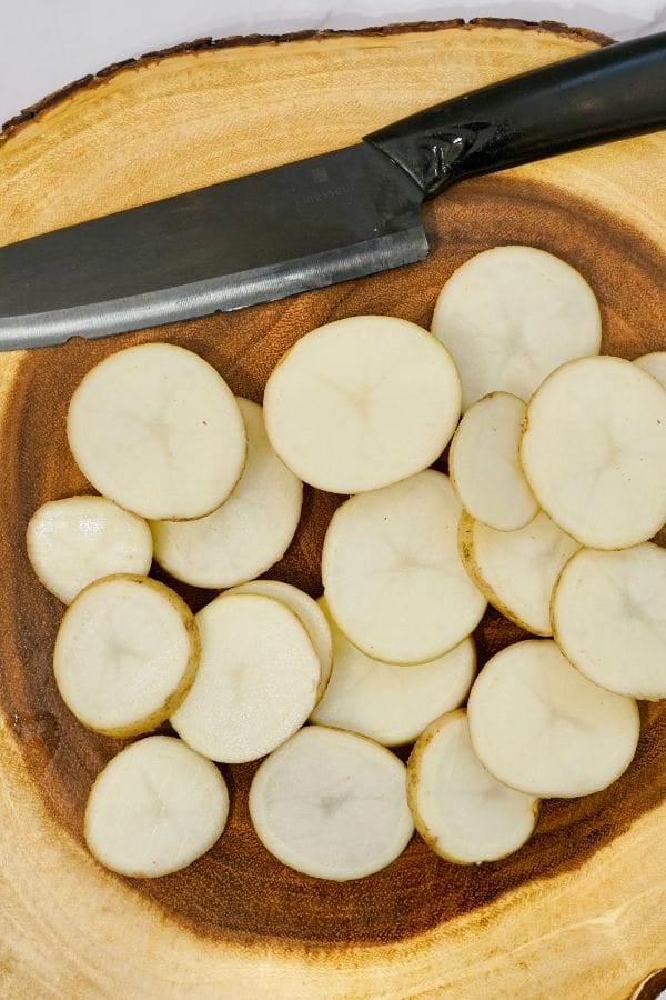 Sliced potatoes and a knife on a cutting board