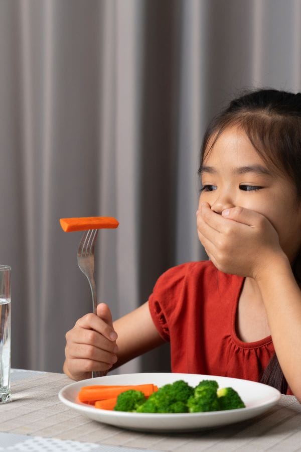 a picky toddler gagging looking at a carrot