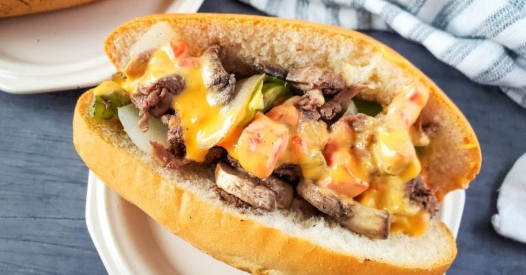 close up of cheese dip philly cheesesteak sandwich on aplate