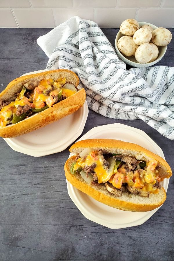 two philly cheesesteak sandwiches on a plate