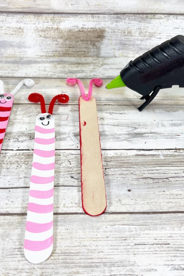 hot glue gun gluing pipe cleaner antennae onto butterfly craft