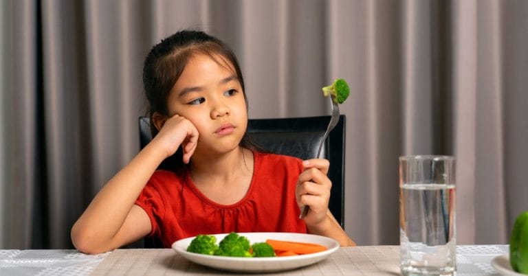 a child looking at vegetables unhappliy