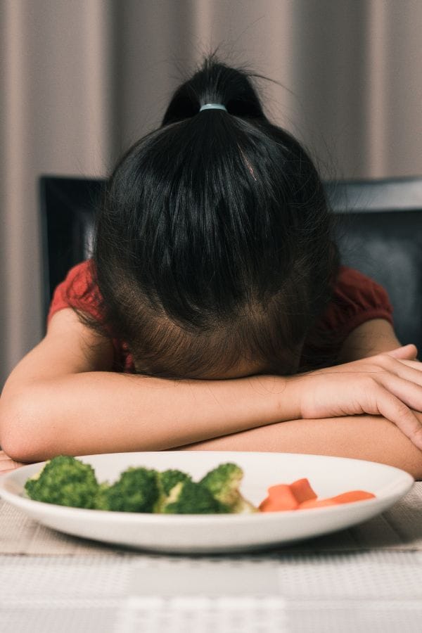 picky eater that is upset and laying her head down on the table