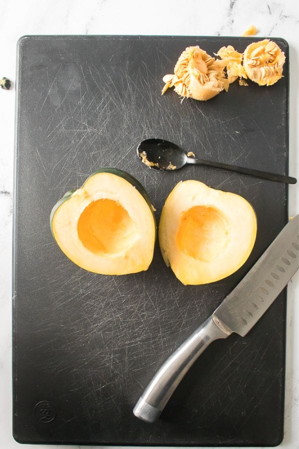 acorn squash being cut in half and seeds removed
