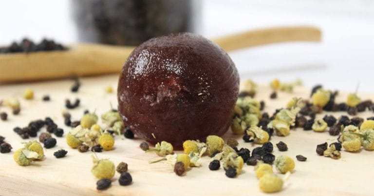 elderberry cold tea bomb on a board with chamomille and elderberries