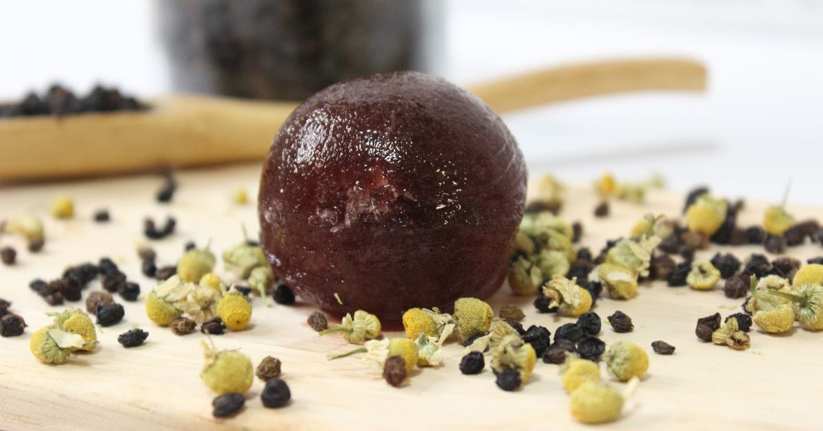 elderberry cold tea bomb on a board with chamomille and elderberries