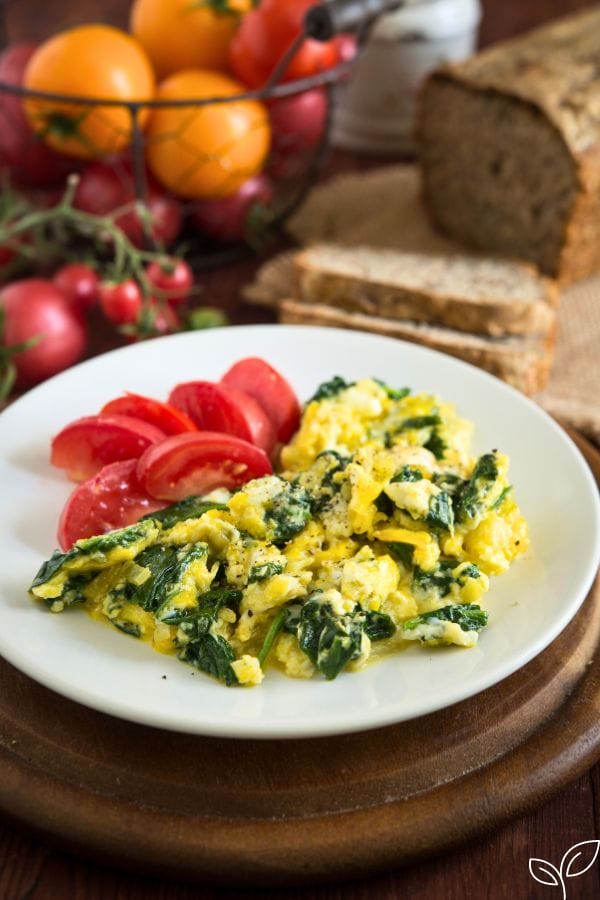scrambled eggs with spinach and cheese on a plate for a toddlers dinner