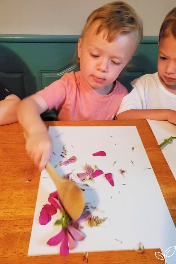 children smashing flowers onto paper for flower printing