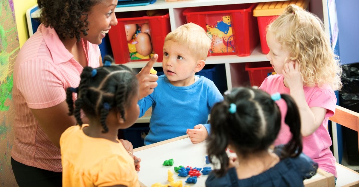 kids learning at a table with a teacher