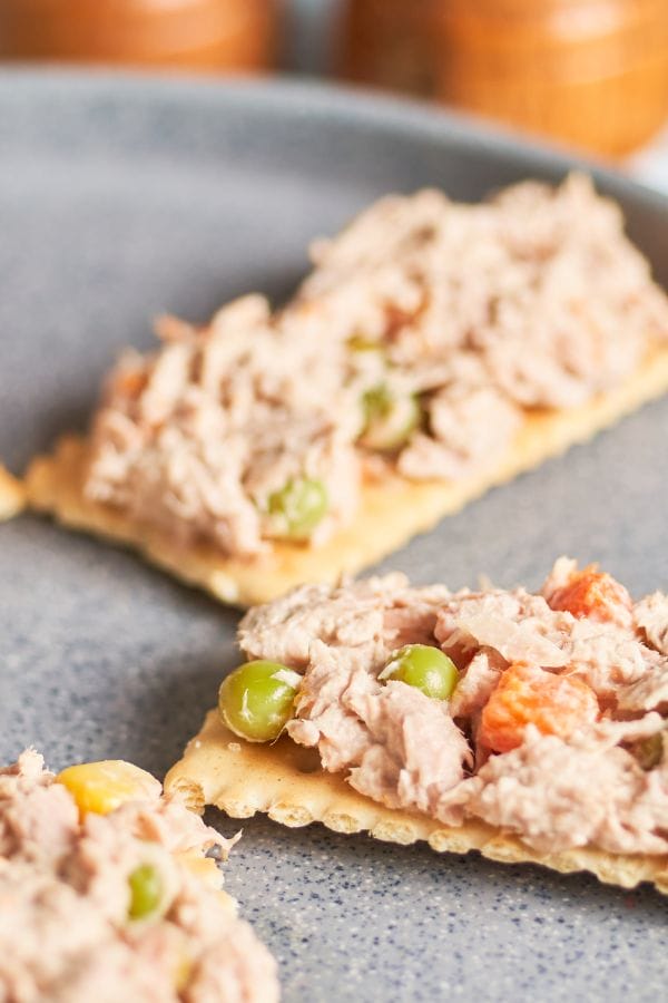 tuna salad mixture on crackers on a counter