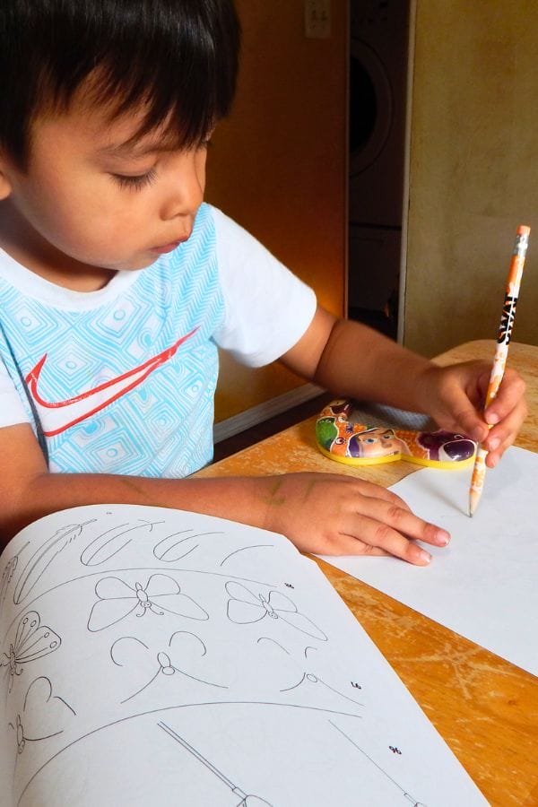 a child drawing with a pencil on a piece of paper