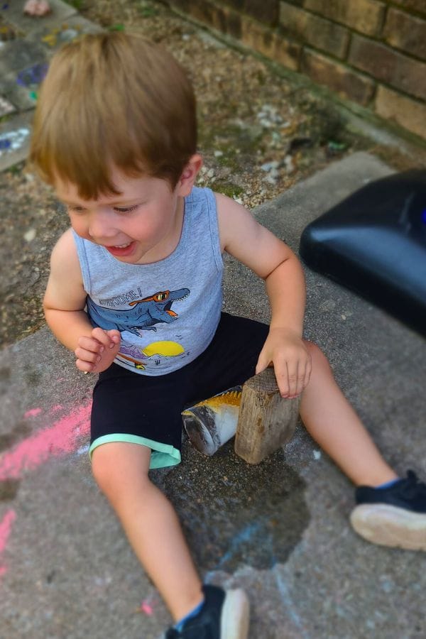 a child breaking a toy out of ice on the playground