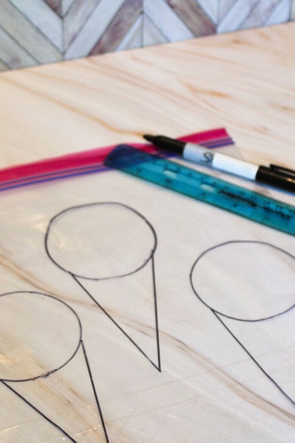 Geometric shapes drawn on a wooden surface, with pens and rulers nearby, create an intricate pattern reminiscent of designs found on Squish Bags.