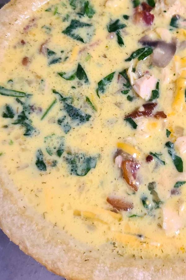 Close-up of a Tuna Bacon and Mushroom Quiche with visible spinach and cheese in a creamy filling.