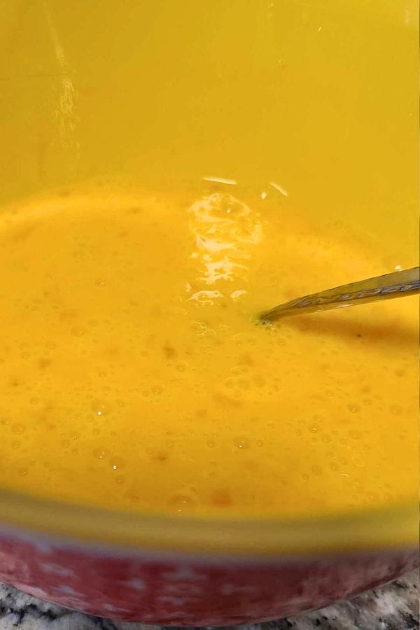 A bowl of whisked eggs with a fork, ready to create delicious broccoli cheese egg cups.