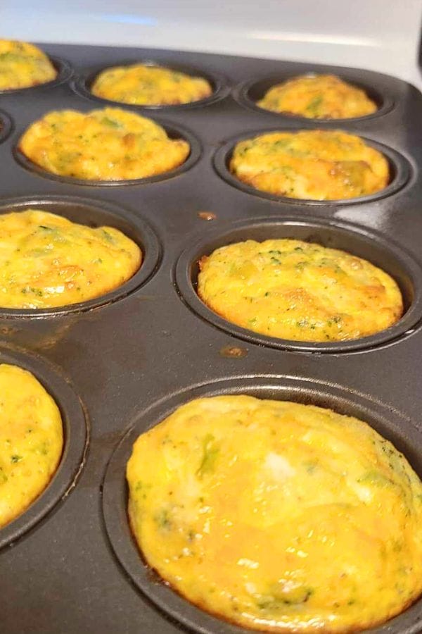 Baked broccoli cheese egg cups with herbs in a muffin tin.