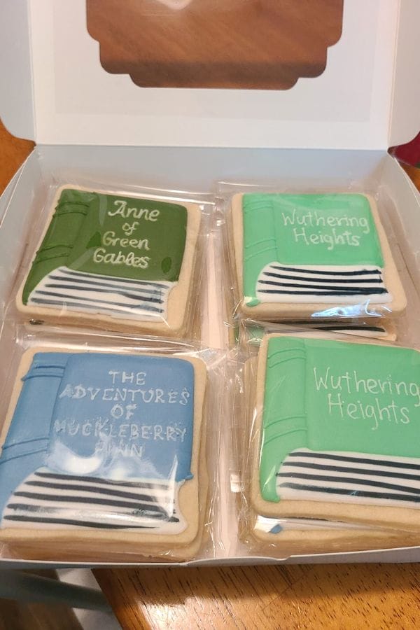Four square cookies shaped like books: "Anne of Green Gables," two "Wuthering Heights," and "The Adventures of Huckleberry Finn" - perfect treats for a Classic Literature Themed Tea Party.