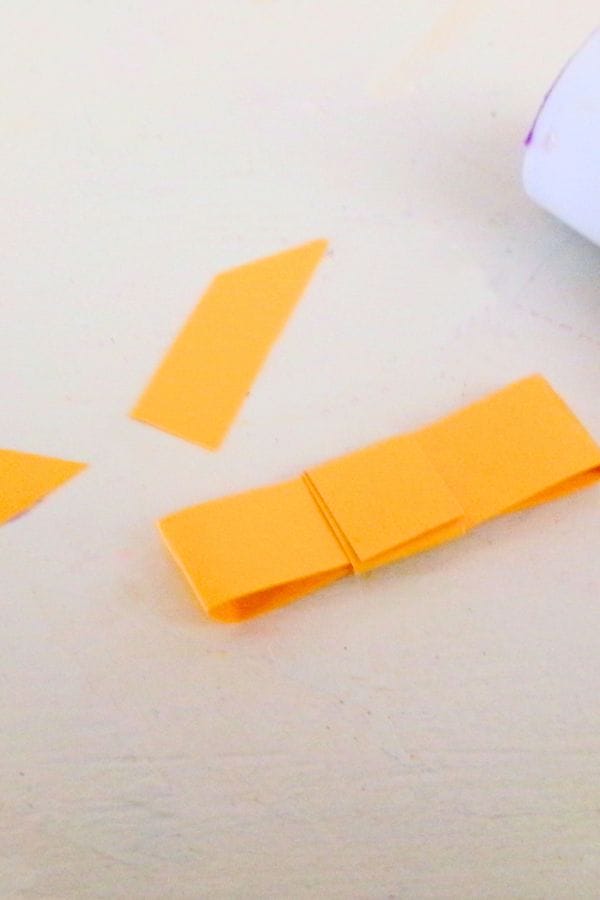 A small piece of folded yellow paper on the table resembles a delicate flower bouquet, with two additional paper pieces nearby.